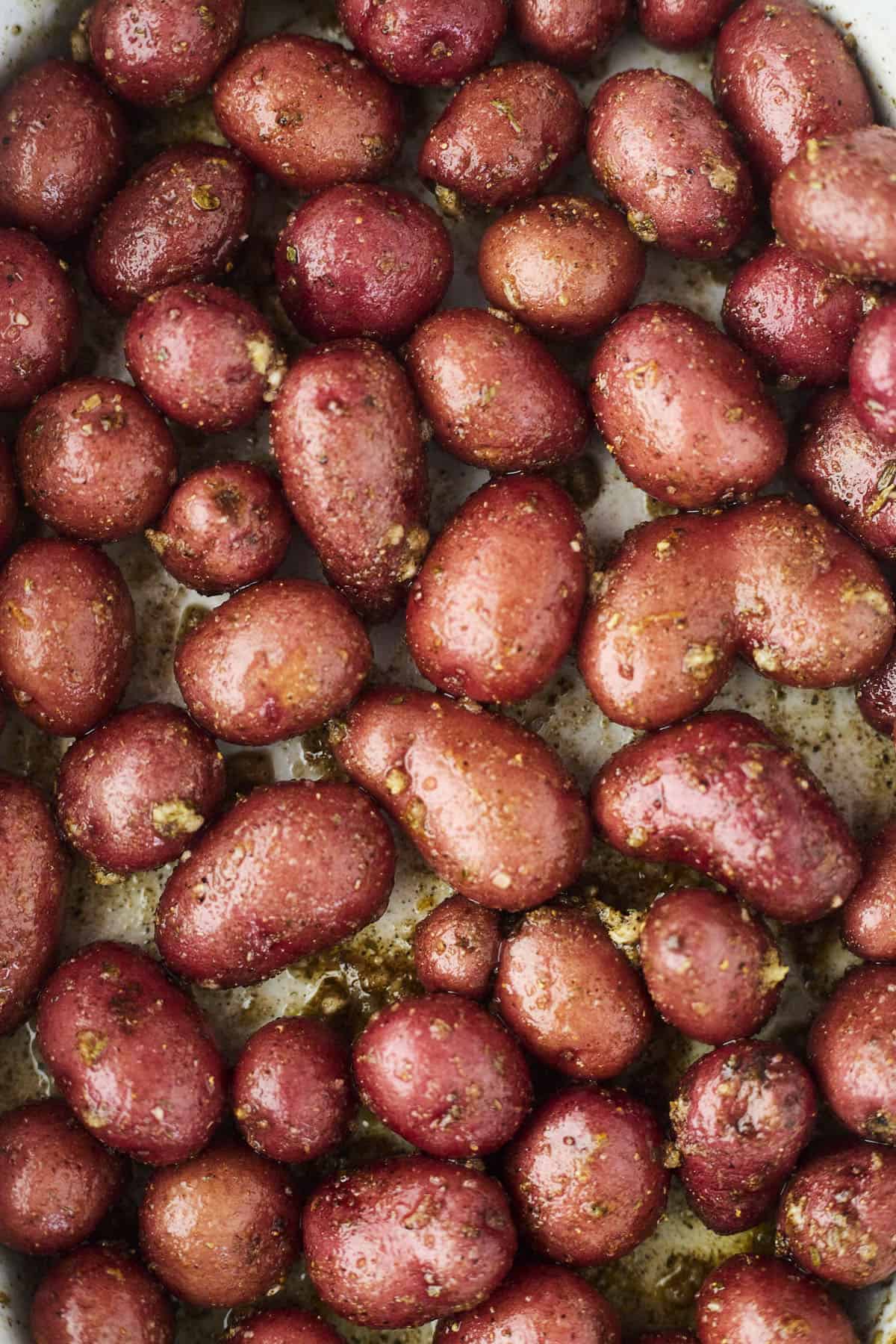 red potatoes tossed with oil and spices on a baking sheet