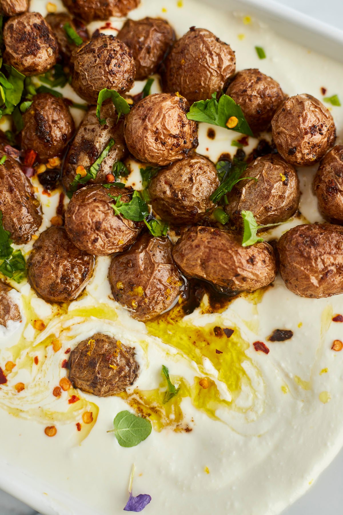 roasted potatoes on top of feta dip topped with red pepper flakes and oil