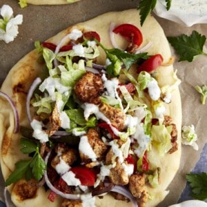 Air fryer chicken shawarma wrap topped with lettuce, tomatoes, and tzatziki.