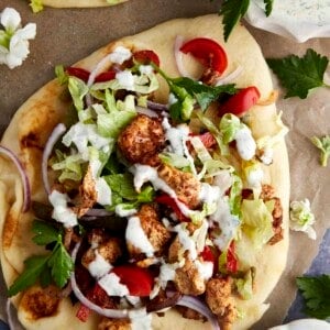 Air fryer chicken shawarma wrap topped with lettuce, tomatoes, and tzatziki.