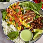 a bowl of southwest chicken salad with a small container of creamy cilantro dressing on top.