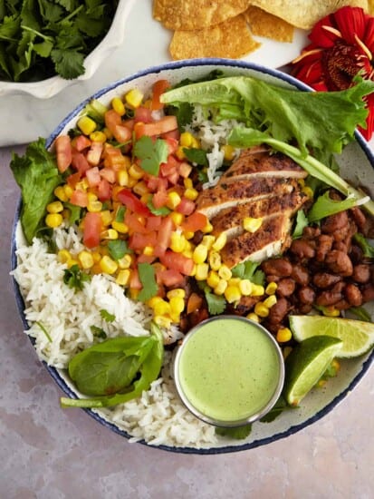 a bowl of southwest chicken salad with a small container of creamy cilantro dressing on top.