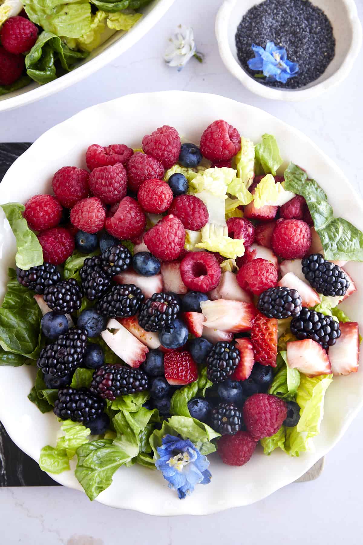 An undressed summer berry salad with romaine, strawberries, blackberries, raspberries, and blueberries. 