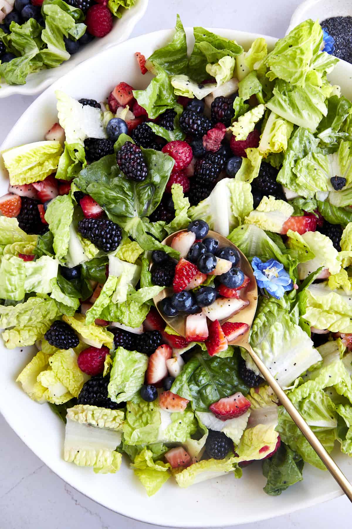 A spoonful of berries on top of a summer berry salad tossed with poppy seed dressing. 