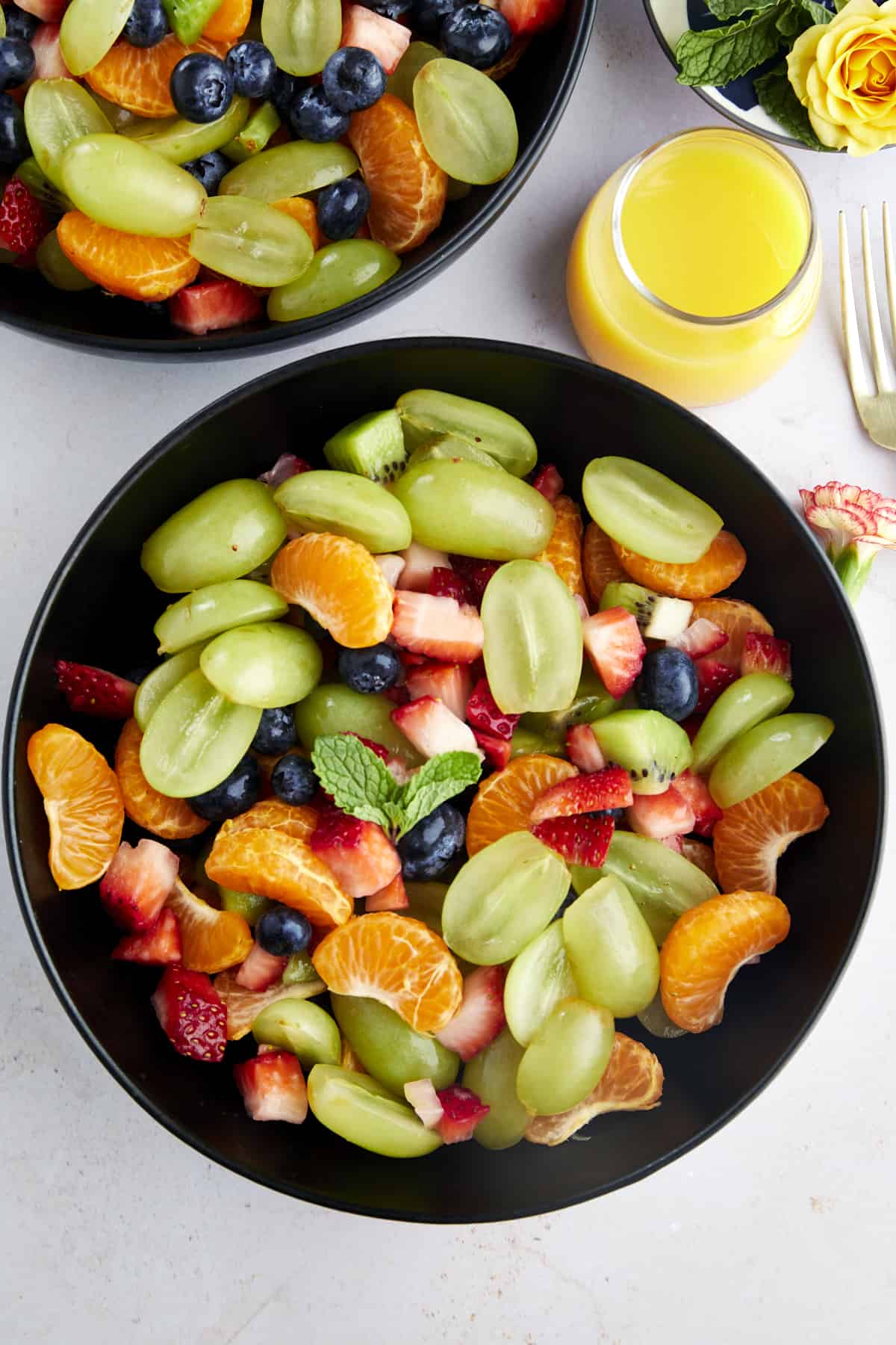 overhead image of a bowl of easy fruit salad with orange juice dressing on the side