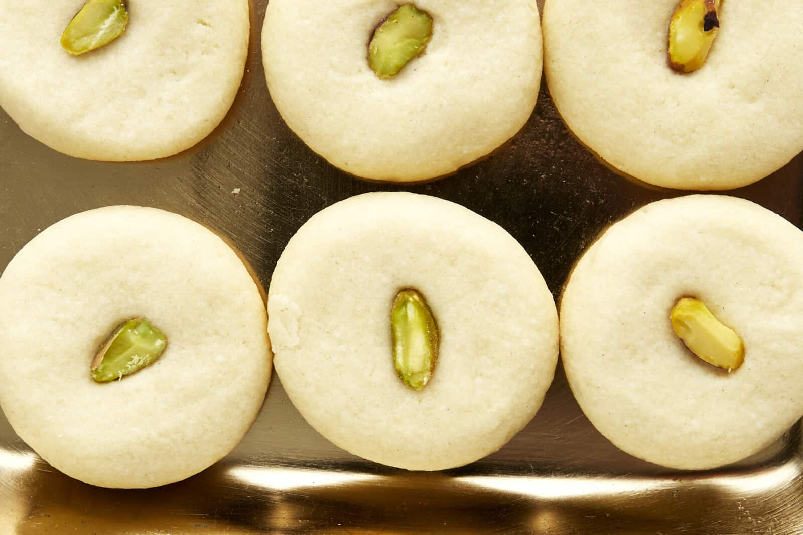 Close up image of ghraybeh cookies topped with pistachio halves.