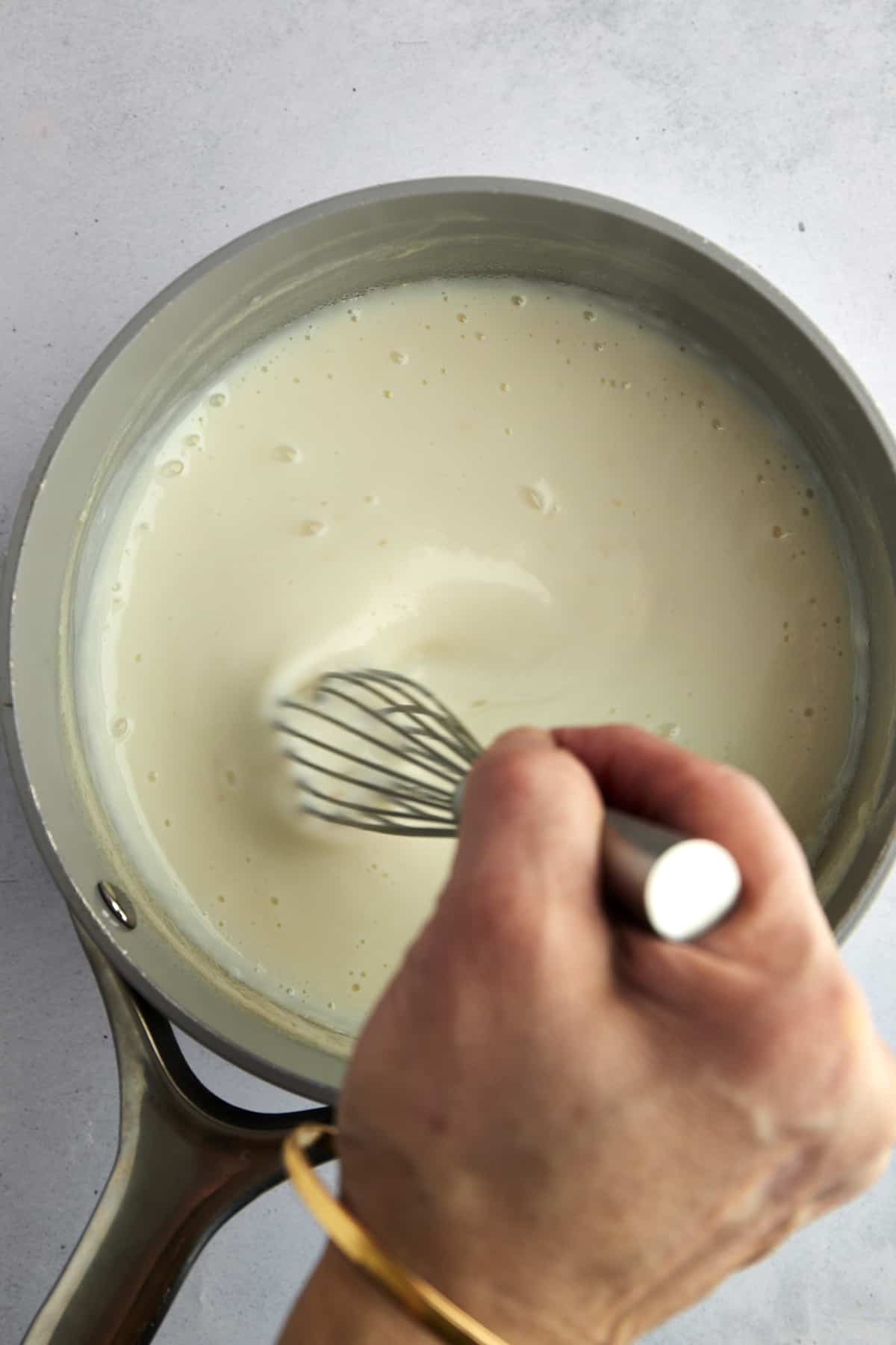 A hand whisking milk pudding. 