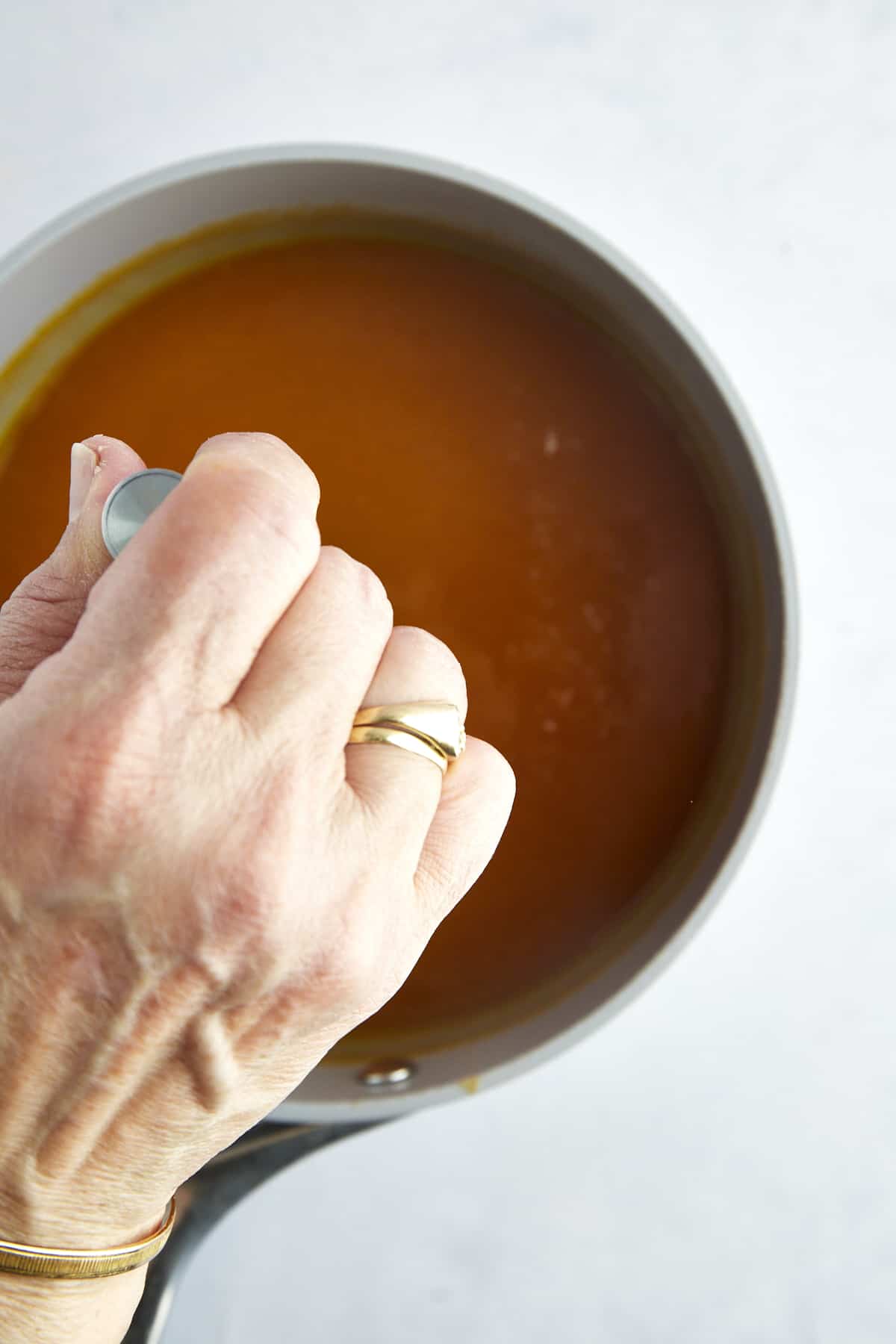 A hand stirring Amardeen in a pot. 