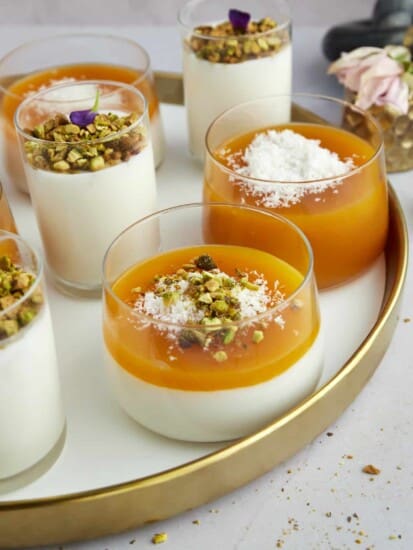 Pots of Muhallebi Amardeen Pudding topped with coconut flakes and chopped pistachios.