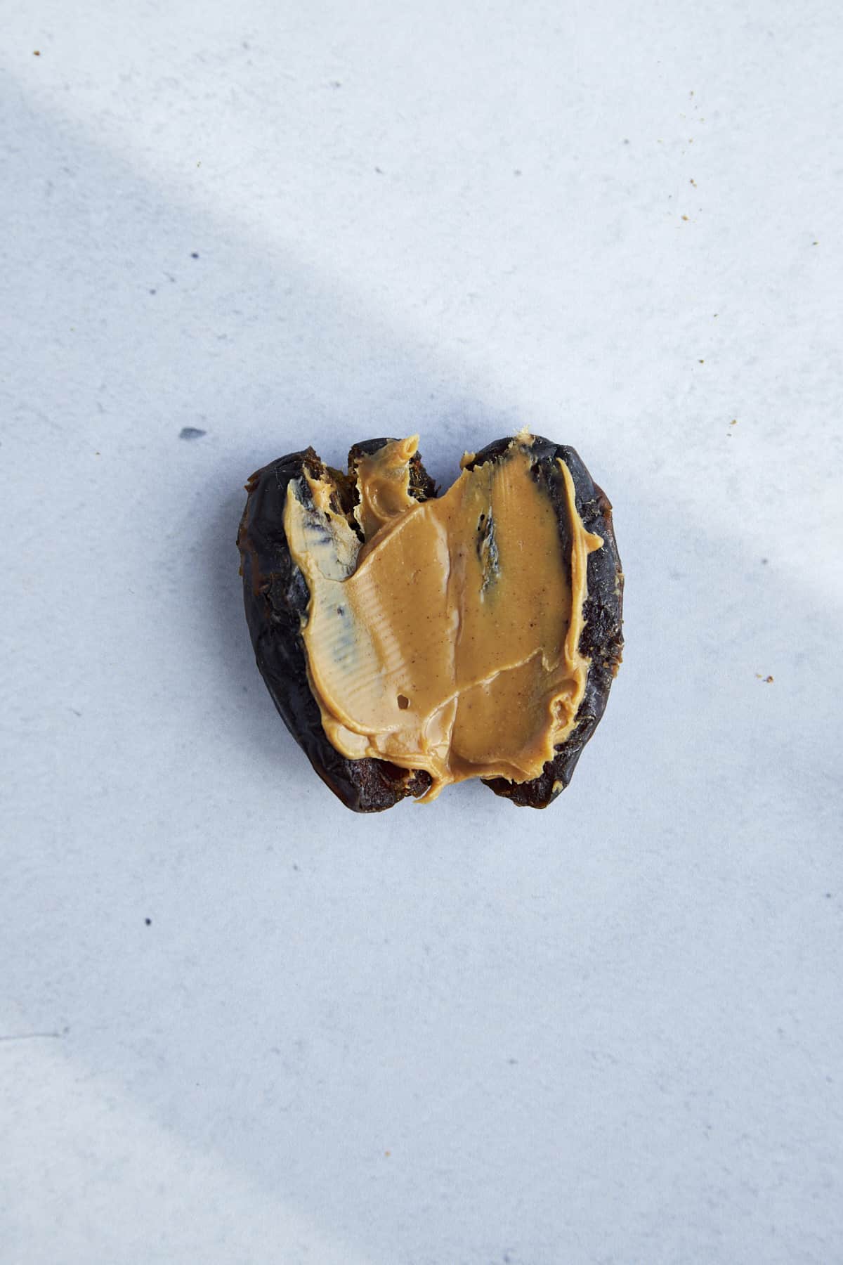 A date sliced in half with peanut butter spread on top. 