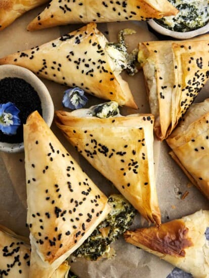 Baked spanakopita triangles topped with black sesame seeds.