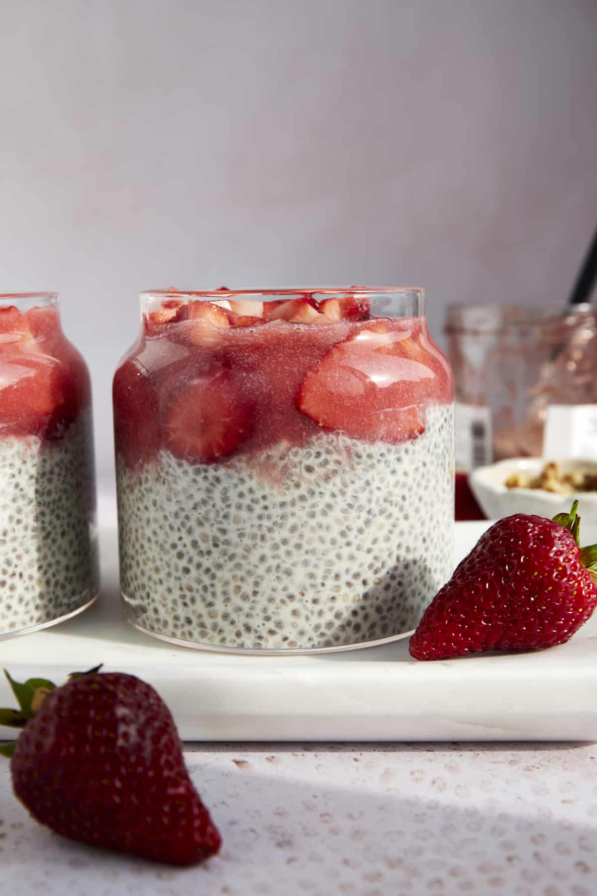A jar of strawberry chia pudding topped with strawberry purée and fresh strawberries. 