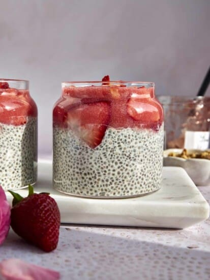 Side view of a jar of strawberry chia pudding topped with strawberry puree and strawberry slices.