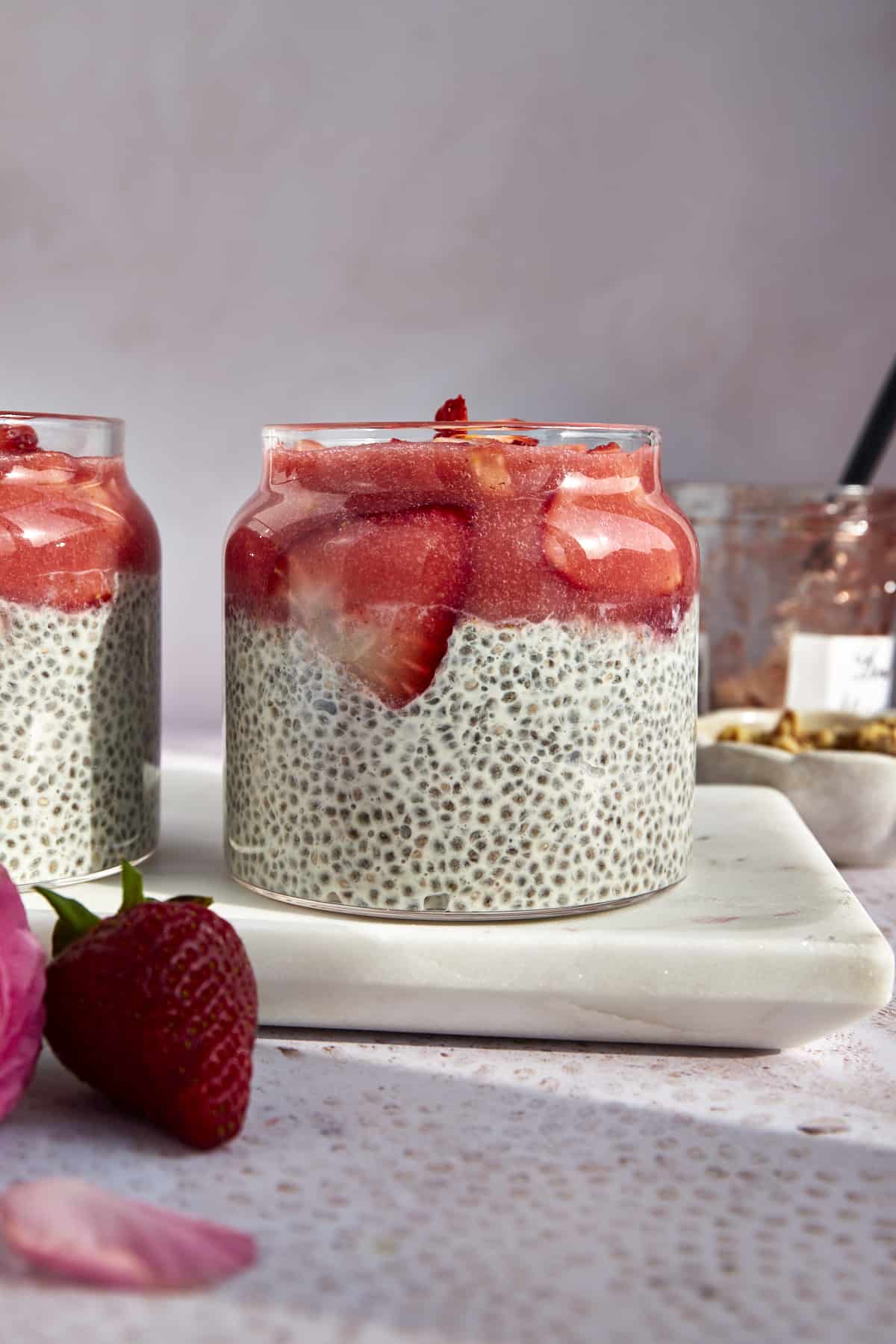 A jar of chia pudding topped with strawberry purée and sliced strawberries.