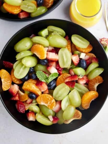 overhead image of a bowl of easy fruit salad with orange juice dressing on the side