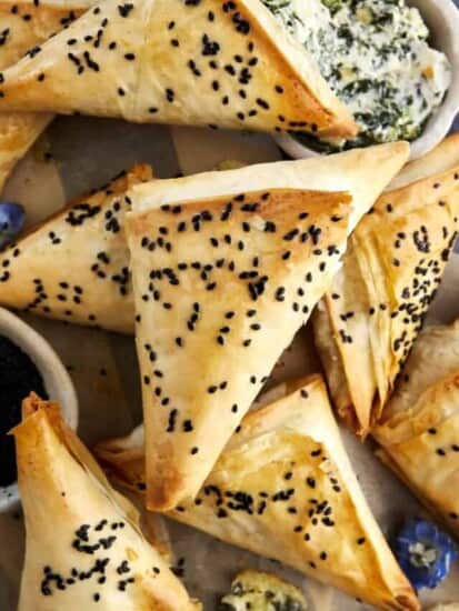 Baked spanakopita triangles topped with black sesame seeds.