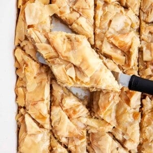 A baking dish full of easy baklava with a piece being lifted with a spatula.