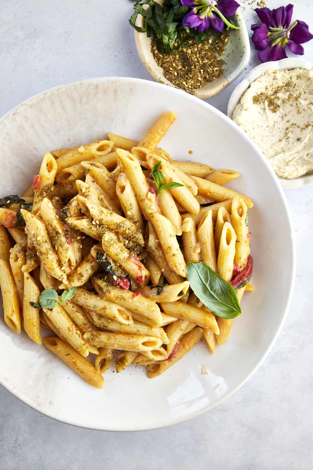 a white plate of hummus pasta with penne