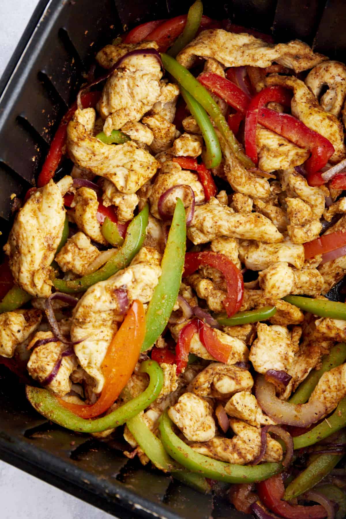 Cooked air fryer chicken fajitas in an air fryer basket. 