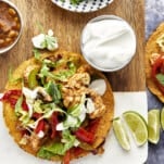 An air fryer chicken fajita taco with sour cream and lime wedges on the side.
