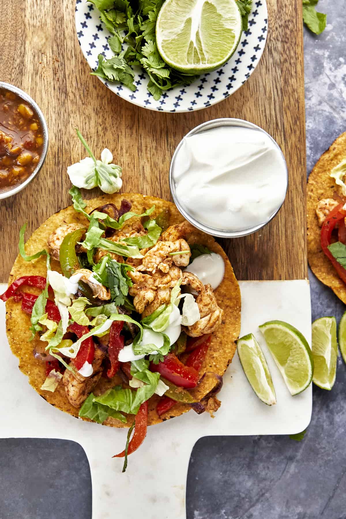 An air fryer chicken fajita taco on a corn tortilla with lettuce on top and sour cream on the side. 