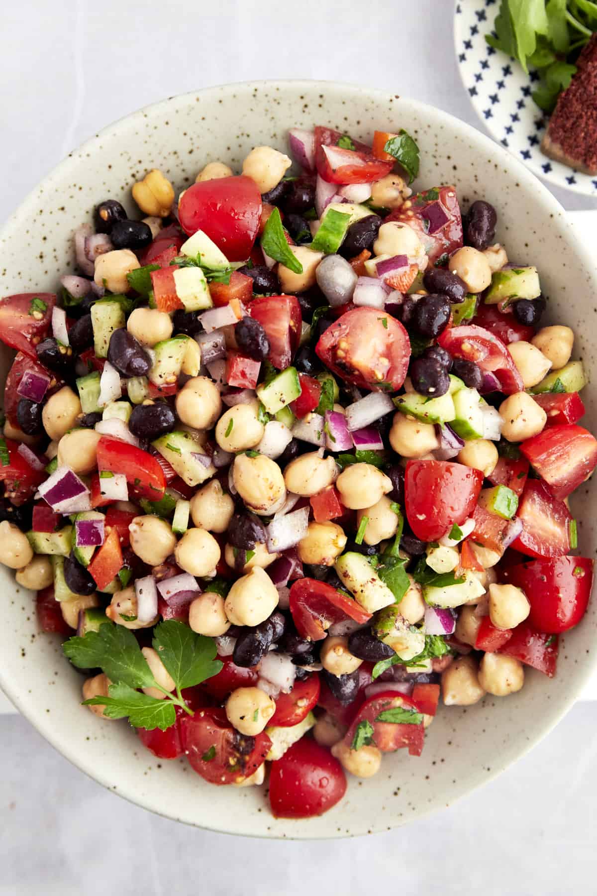 A bowl of Balela Salad with black beans, chickpeas, and veggies.