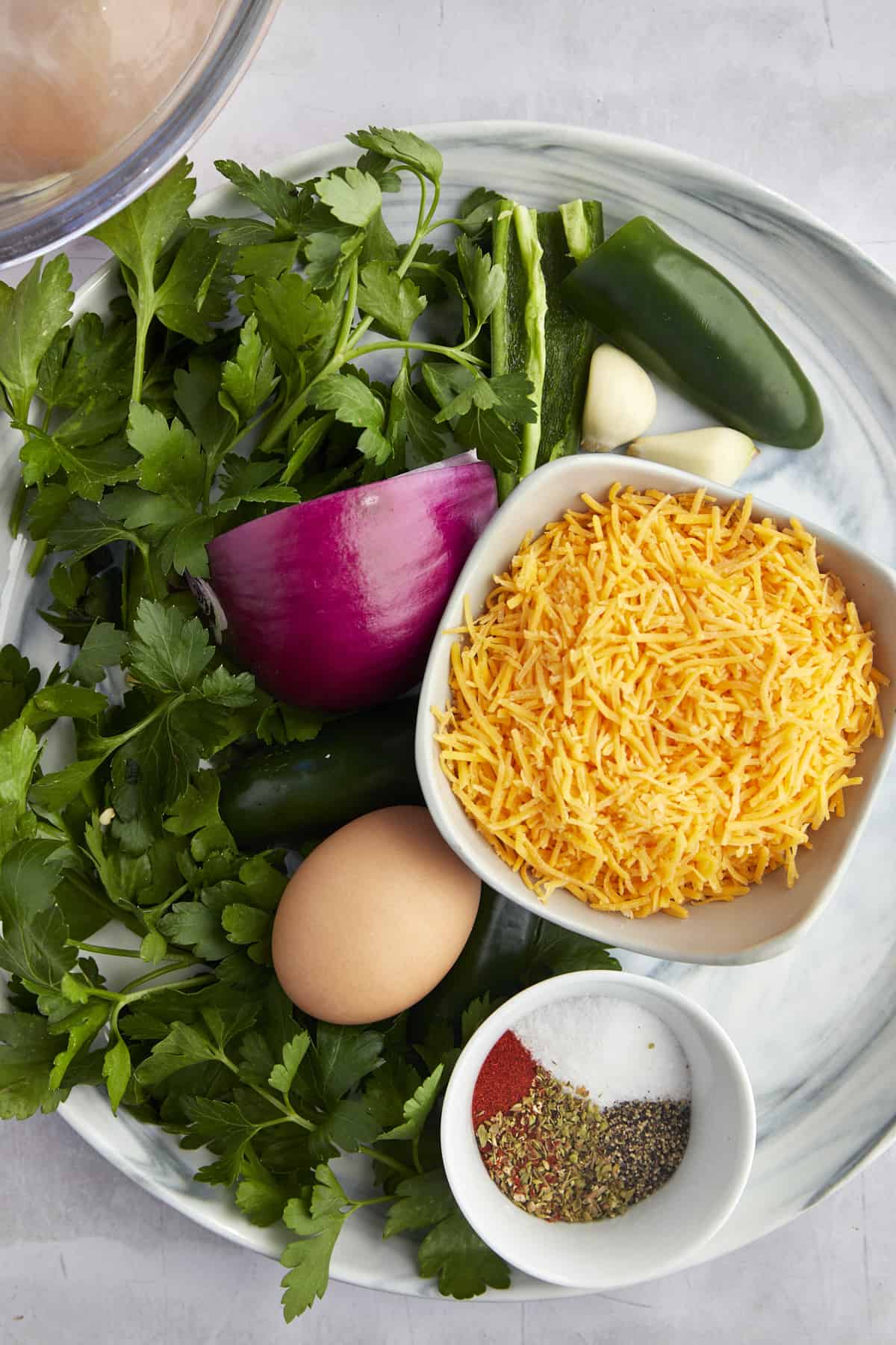 Fresh parsley, shredded Cheddar cheese, red onion, jalapeño, garlic cloves, an egg, and spices.