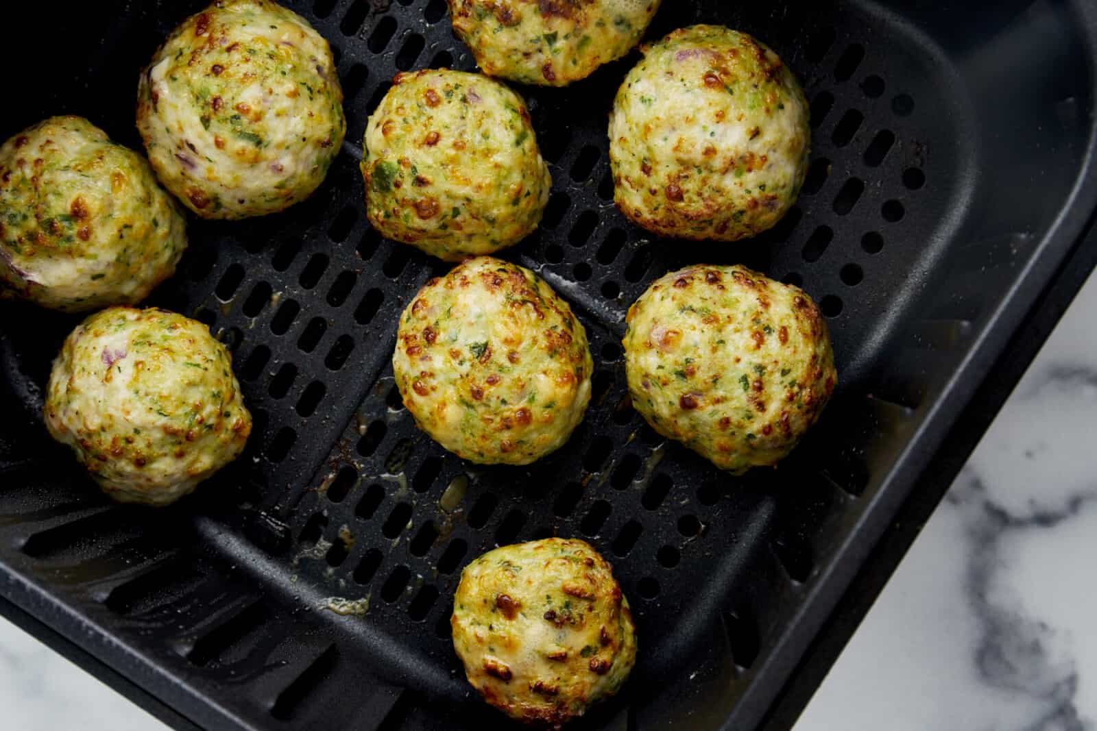 Cooked Air Fryer Jalapeño Cheddar Chicken Meatballs in an air fryer basket. 