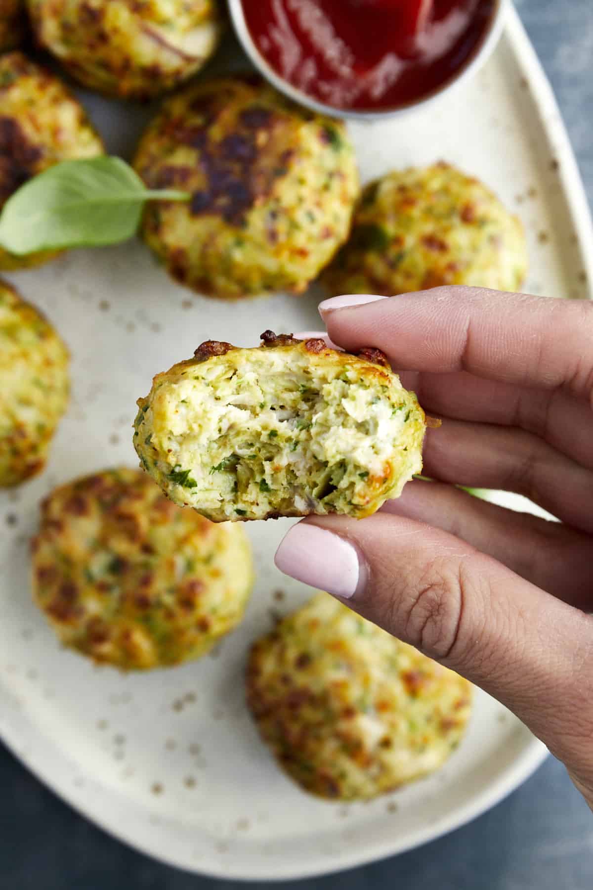 A hand holding an Air Fryer Jalapeño Cheddar Chicken Meatball with a bite missing from it. 