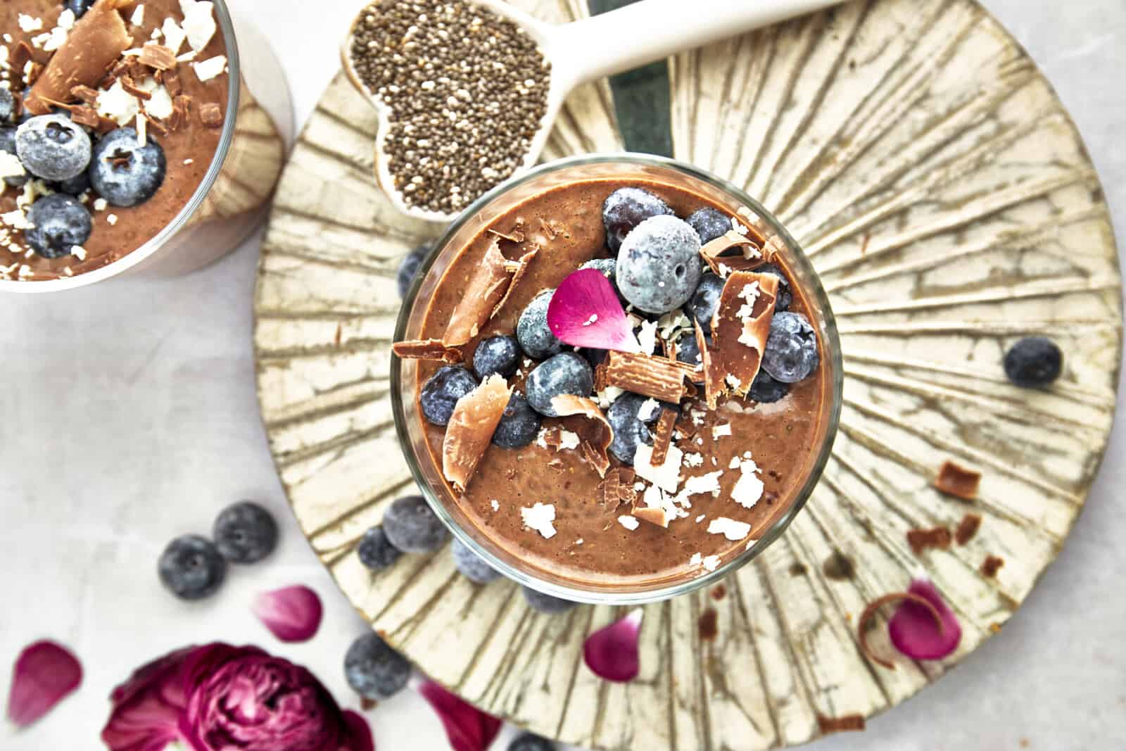 Overhead image of a jar of chocolate chia pudding topped with blueberries, chocolate shavings, and coconut flakes. 