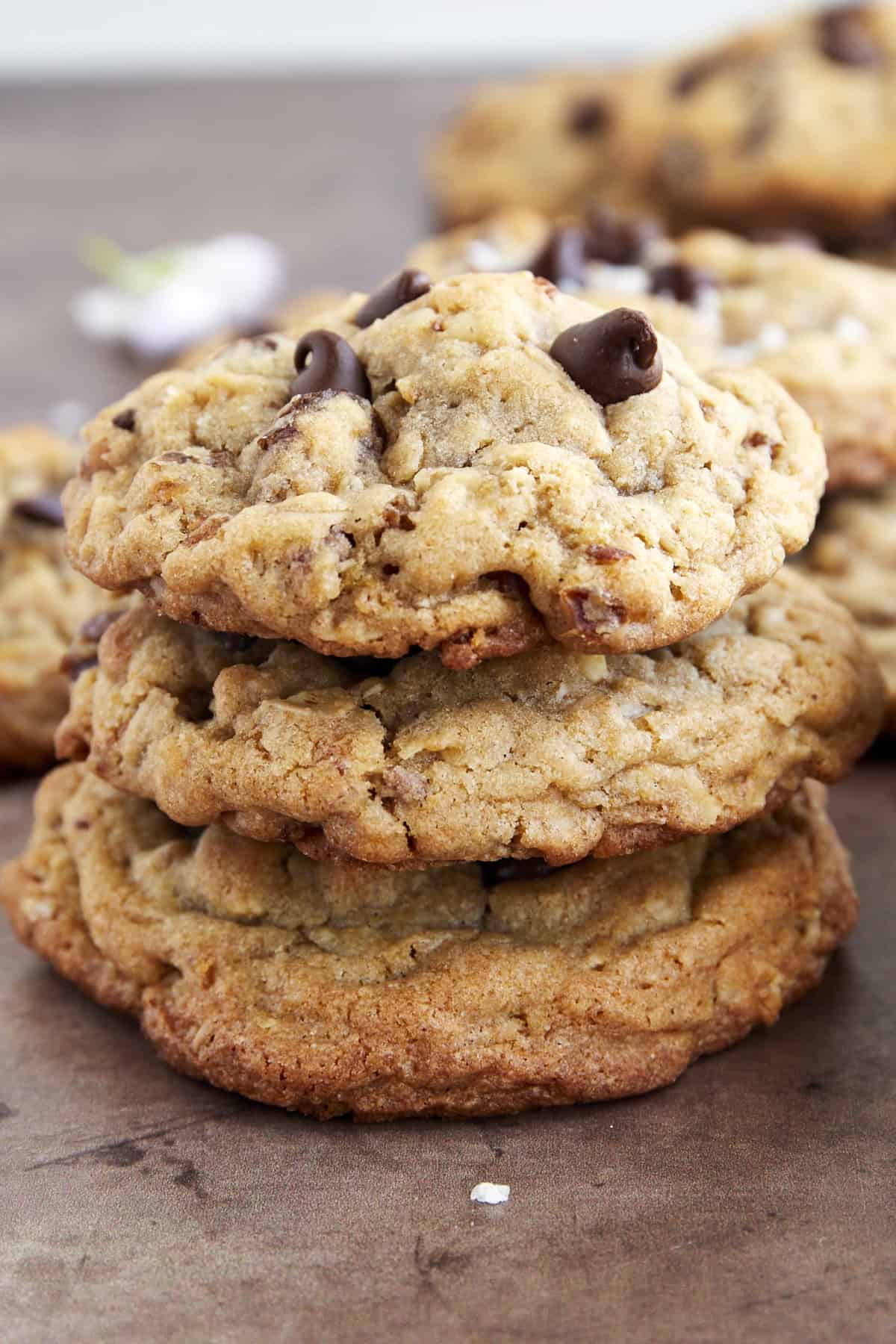 A stack of three golden date cookies with chocolate chips and walnuts on top of each other. 