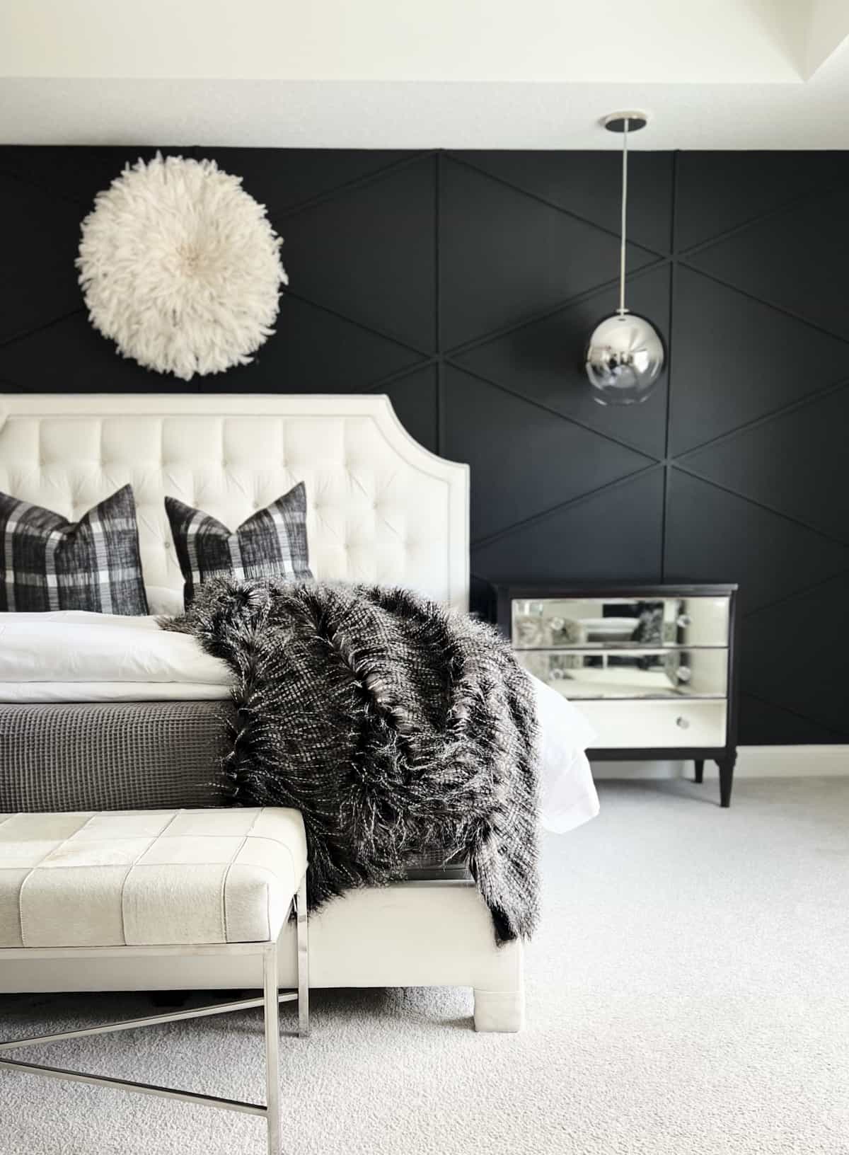 A black accent wall with wood plank diamonds in a bedroom. 