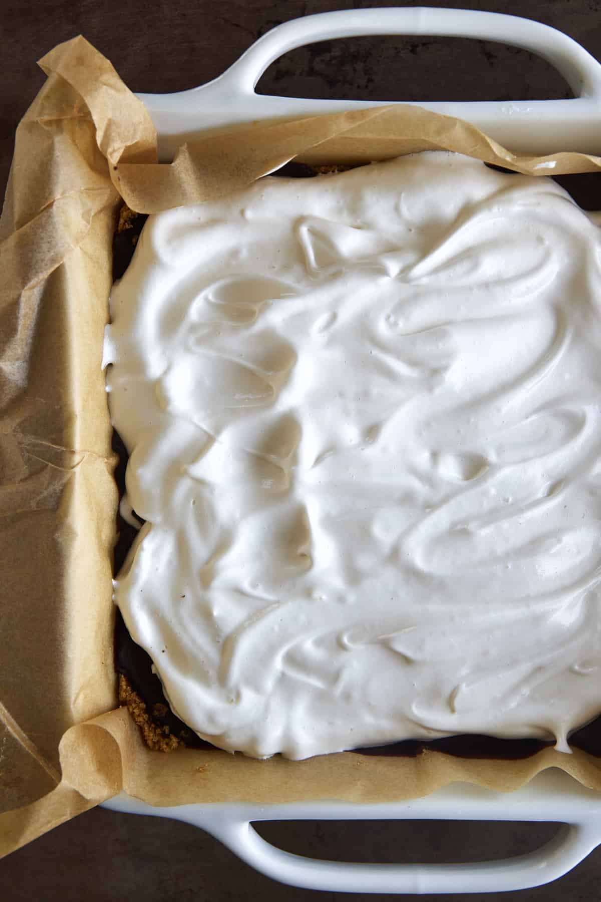 Overhead image of a meringue layer spread over chocolate ganache. 