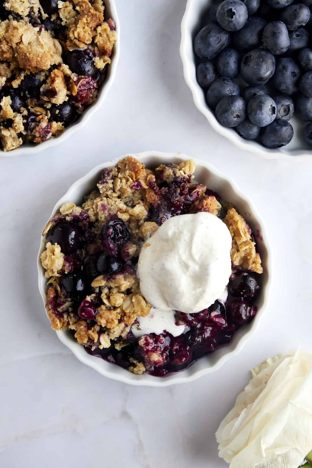 Overhead image of a ramekin full of blueberry crisp topped with vanilla ice cream.