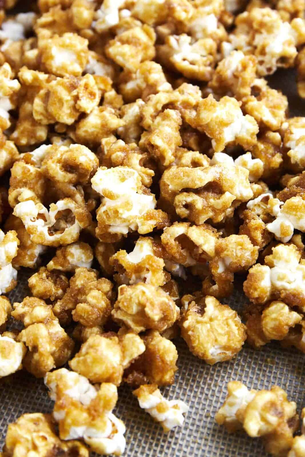 Close up image of homemade caramel popcorn on a baking sheet. 