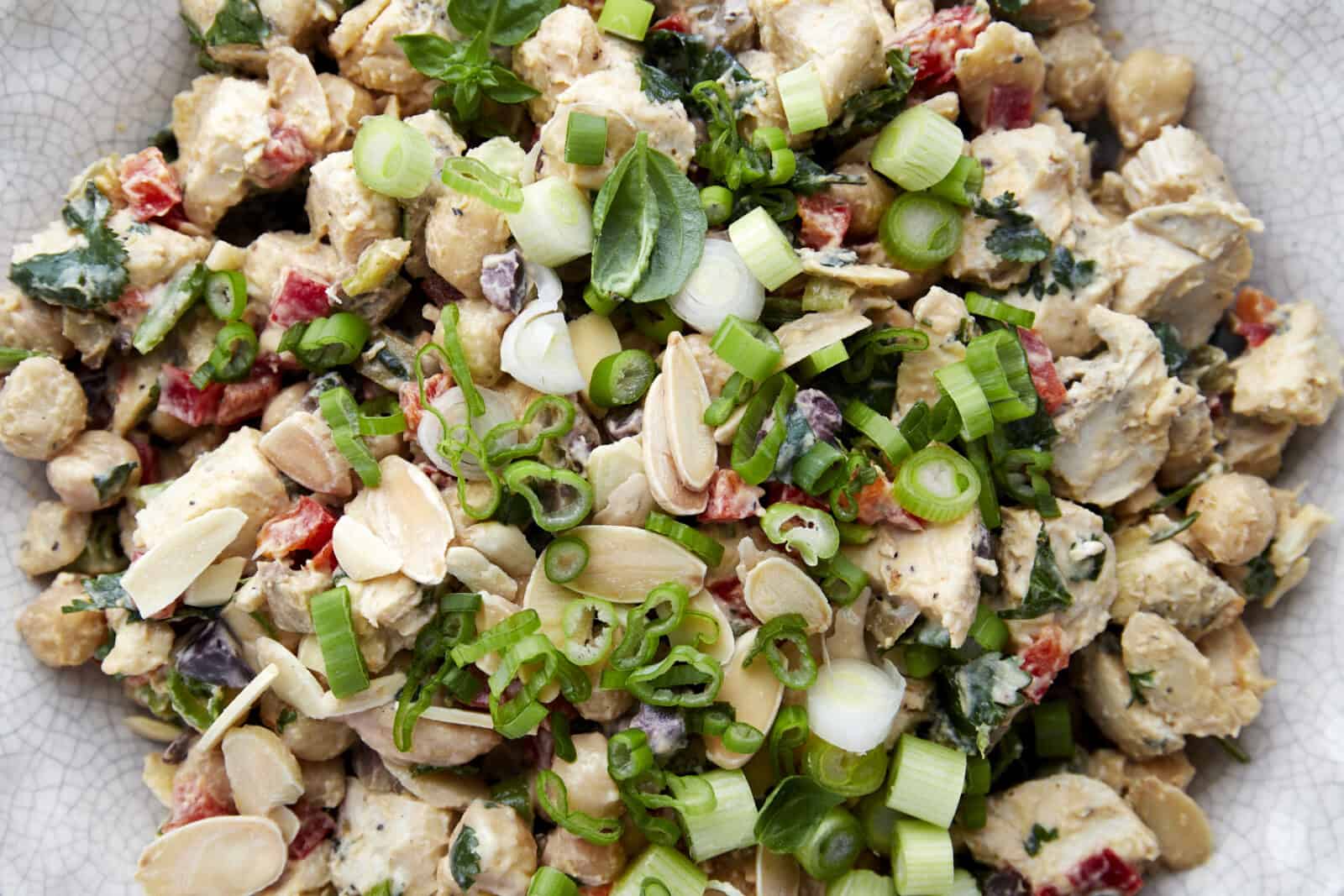 Close up image of chickpea chicken salad topped with slivered almonds and green onions.  