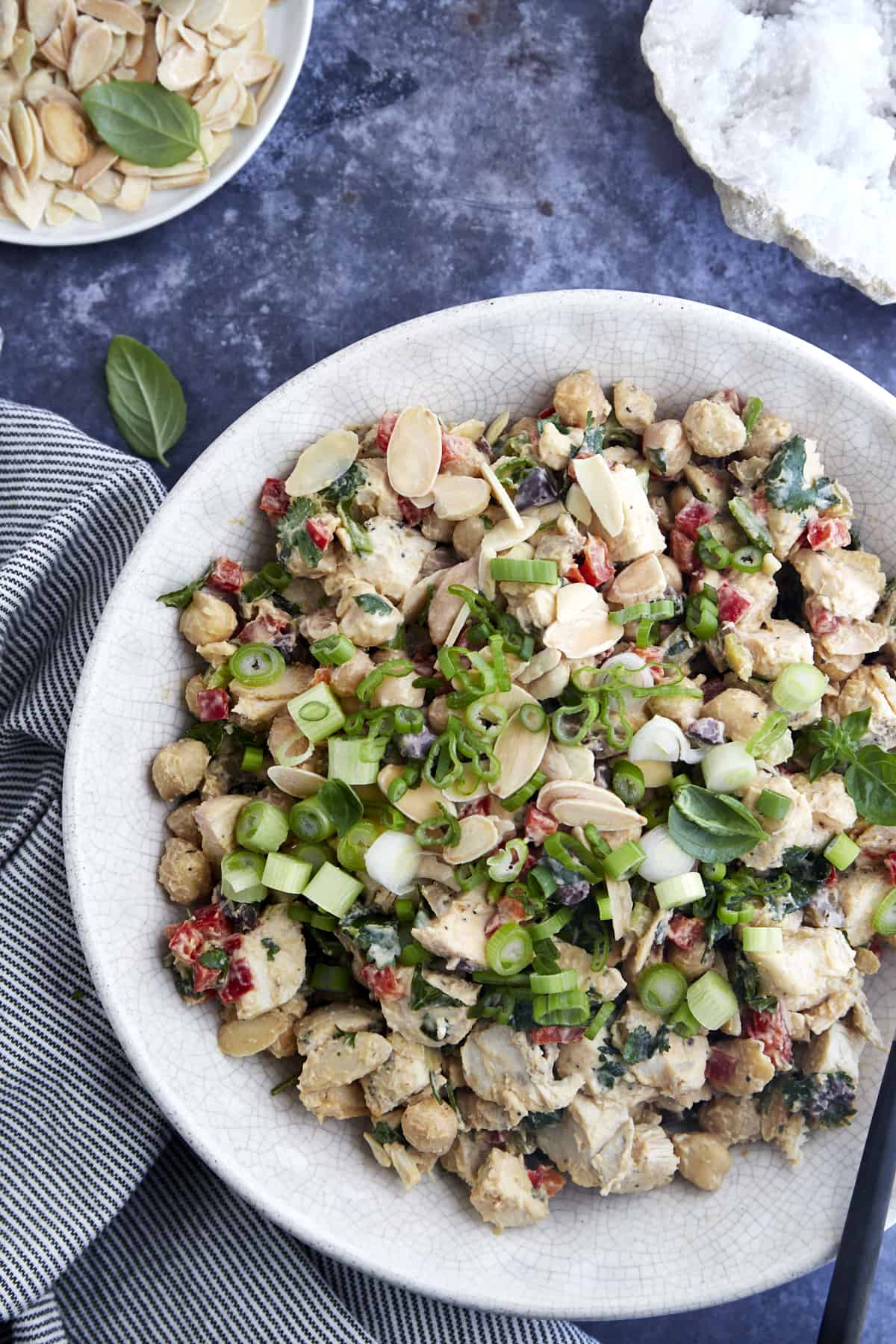 Overhead image of a bowl of chickpea chicken salad topped with slivered toasted almonds and green onions. 