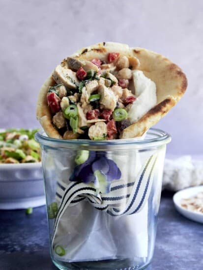 Pita bread stuffed with chickpea chicken salad wrapped and stood upright in a jar.