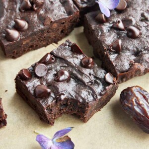 A date brownie square topped with chocolate chips with a bite missing from the corner.