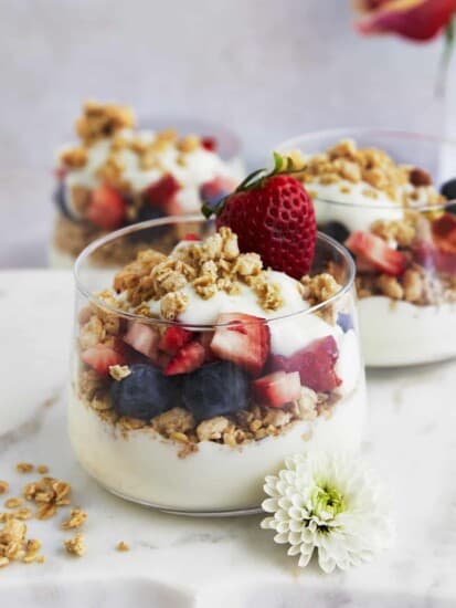 Three jars of fruit and yogurt parfait with blueberries, strawberries, and granola.