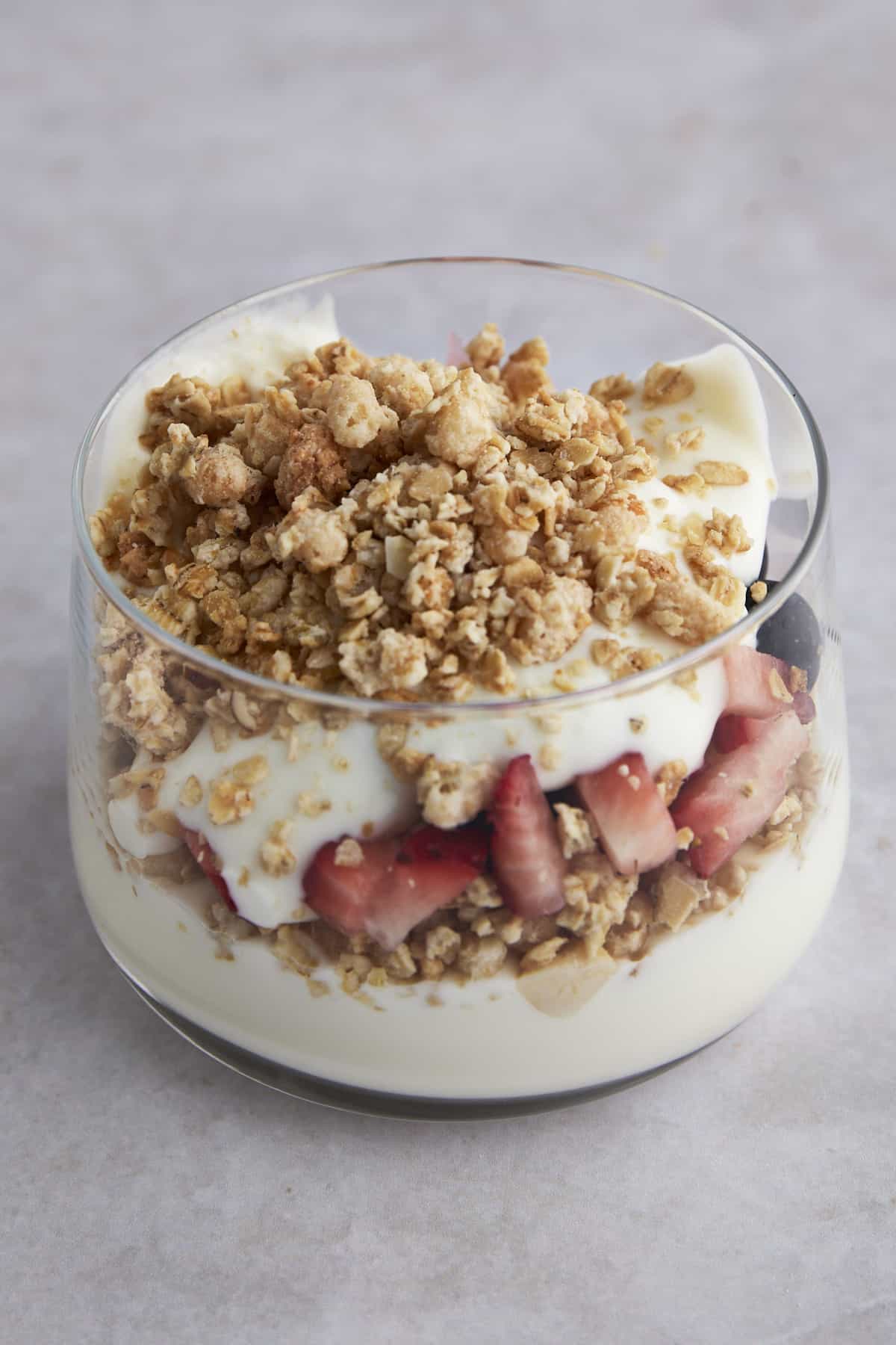 Side view of a fruit and yogurt parfait with yogurt, strawberries and granola. 