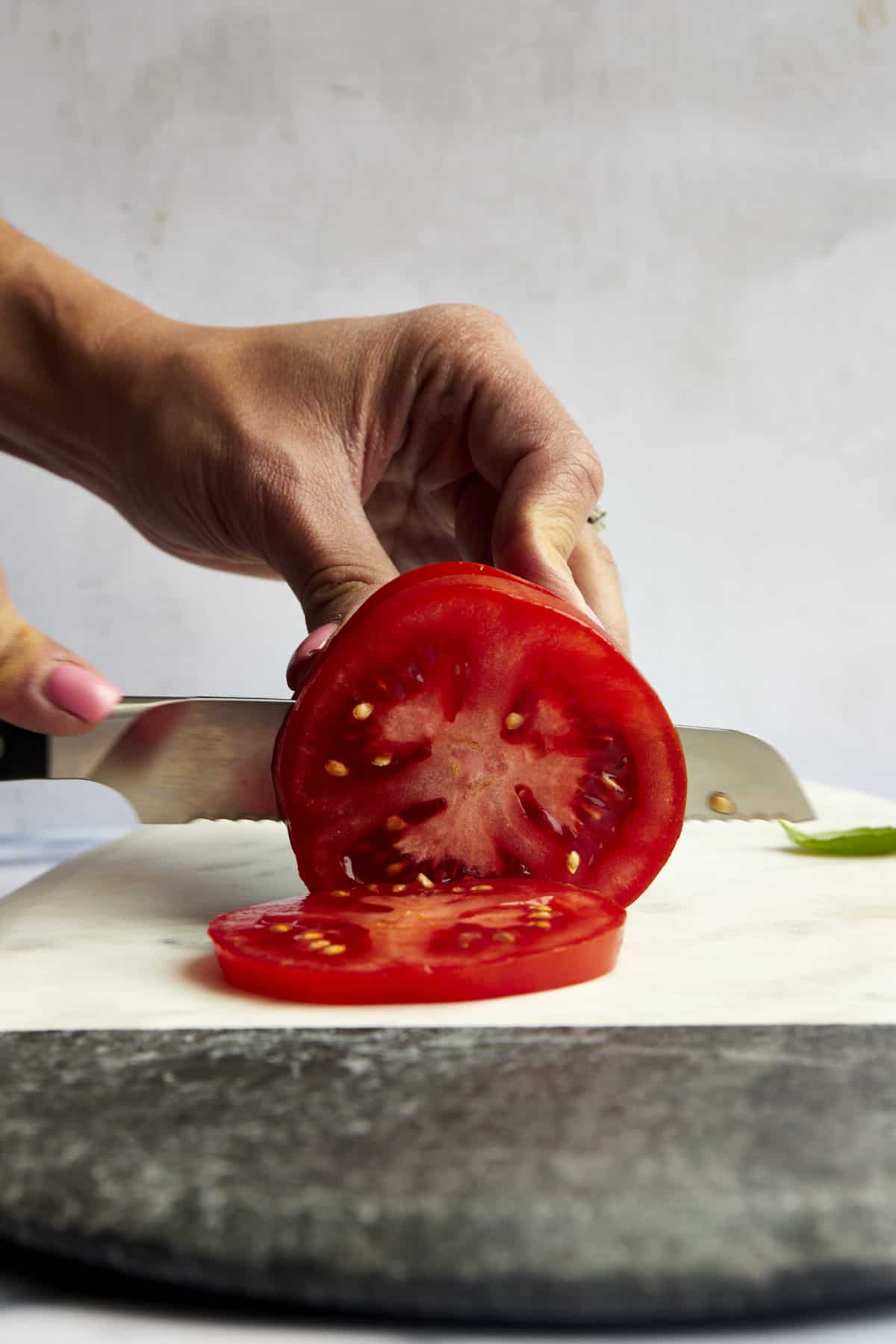 A tomato being cut into slices. 