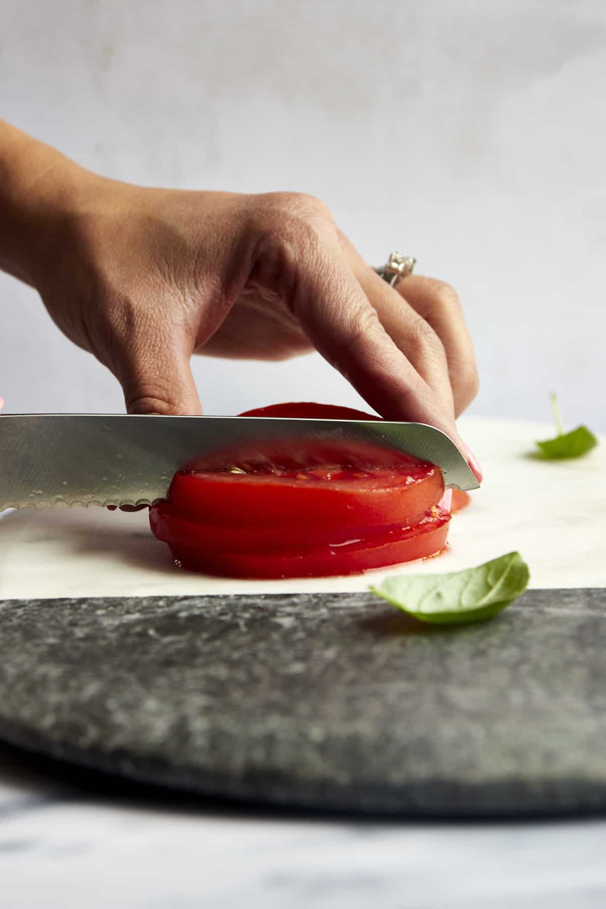 A stack of tomato sliced being diced. 