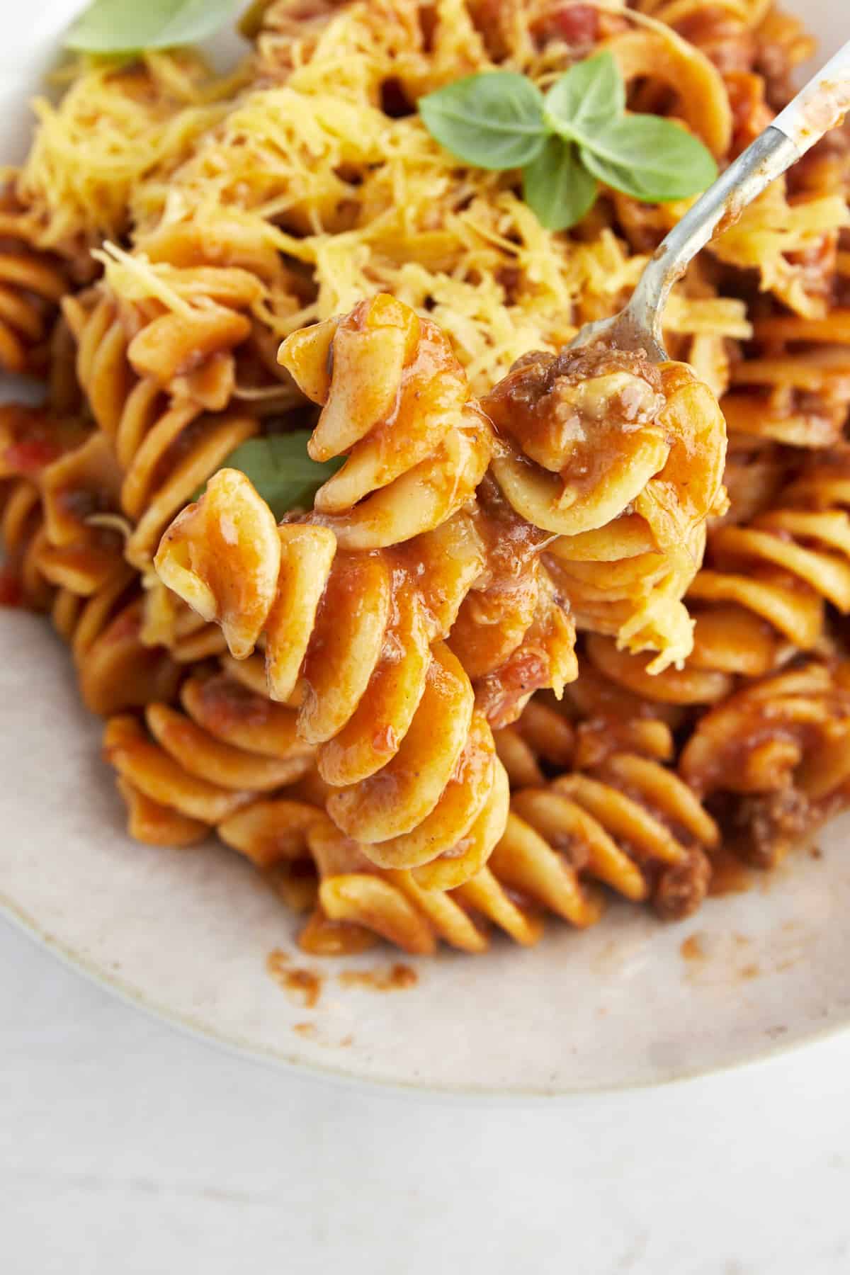 A fork holding a bite of taco pasta with beef. 
