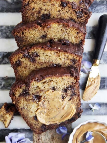 Overhead image of a sliced loaf of chocolate peanut butter banana bread with peanut butter smeared on the first slice.