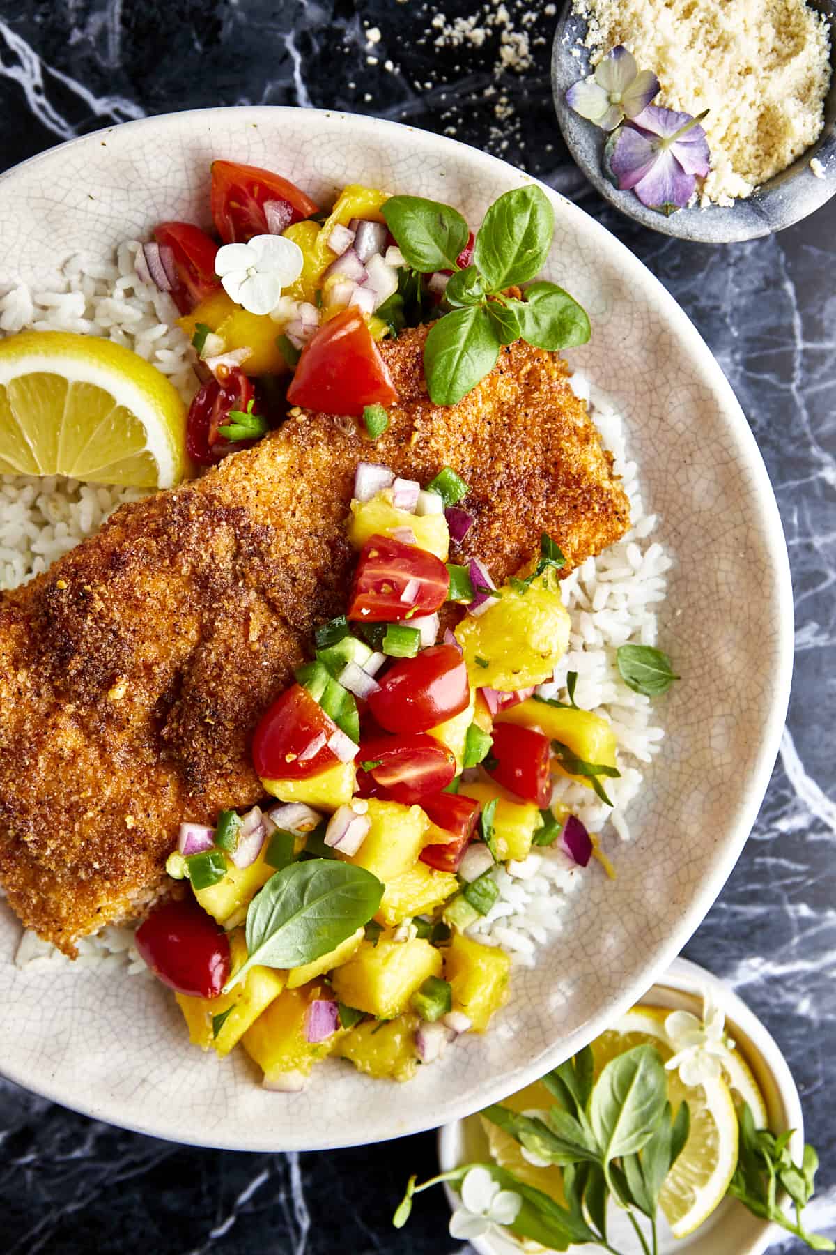 Parmesan crusted salmon with mango salsa on a plate with rice.