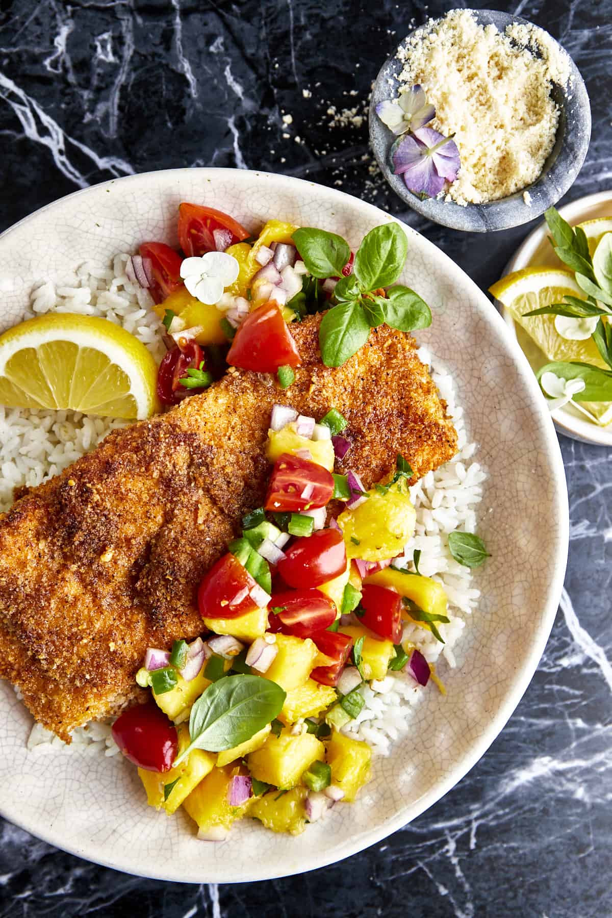 A bowl of Parmesan crusted salmon with mango salsa over a bed of rice. 