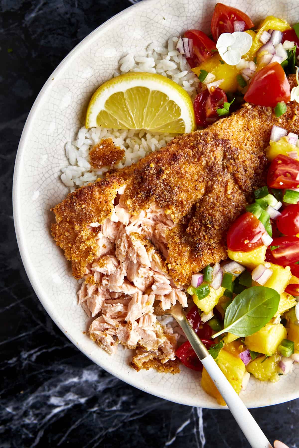 Flaked Parmesan crusted salmon with mango salsa in a bowl over white rice. 