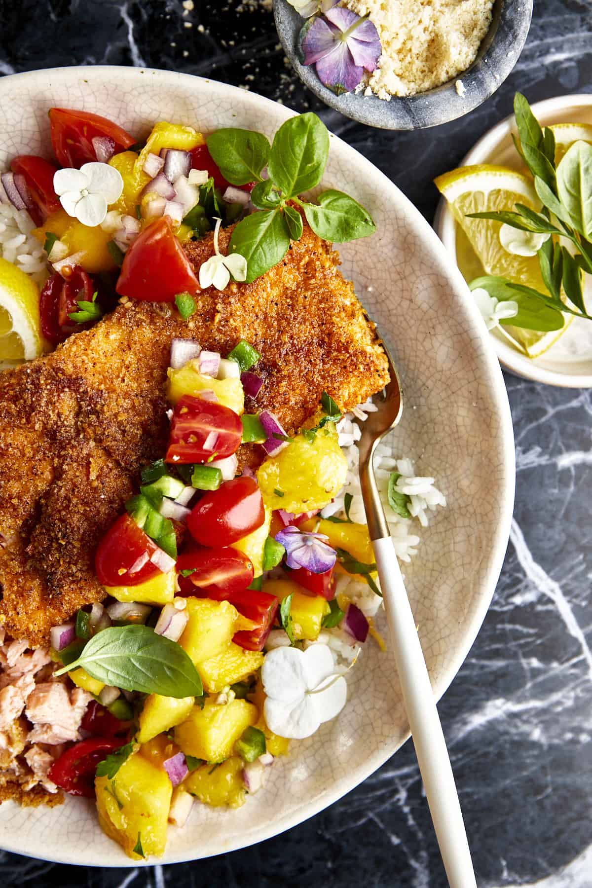 Close up image of a bowl of Parmesan crusted salmon with mango salsa over rice. 