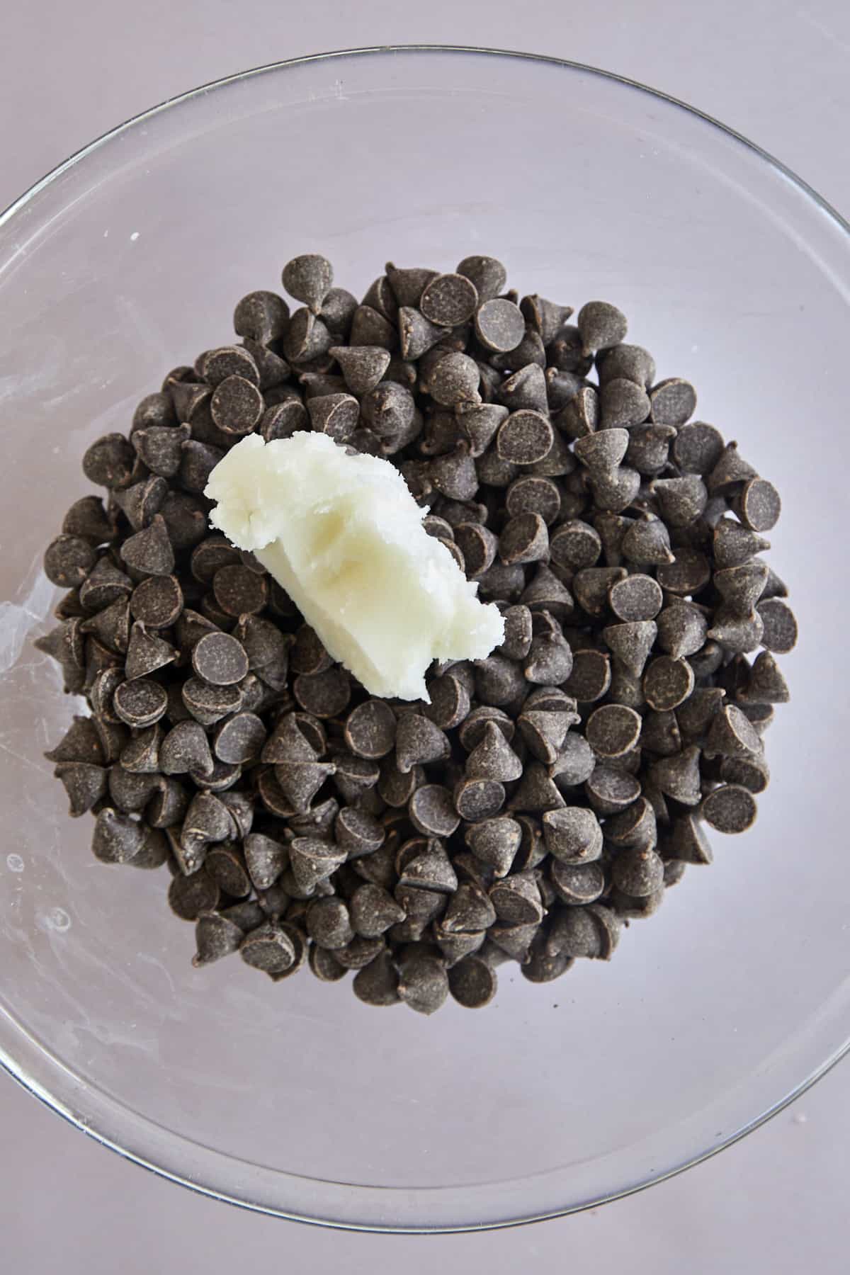 A bowl of semi-sweet chocolate chips with coconut oil on top.